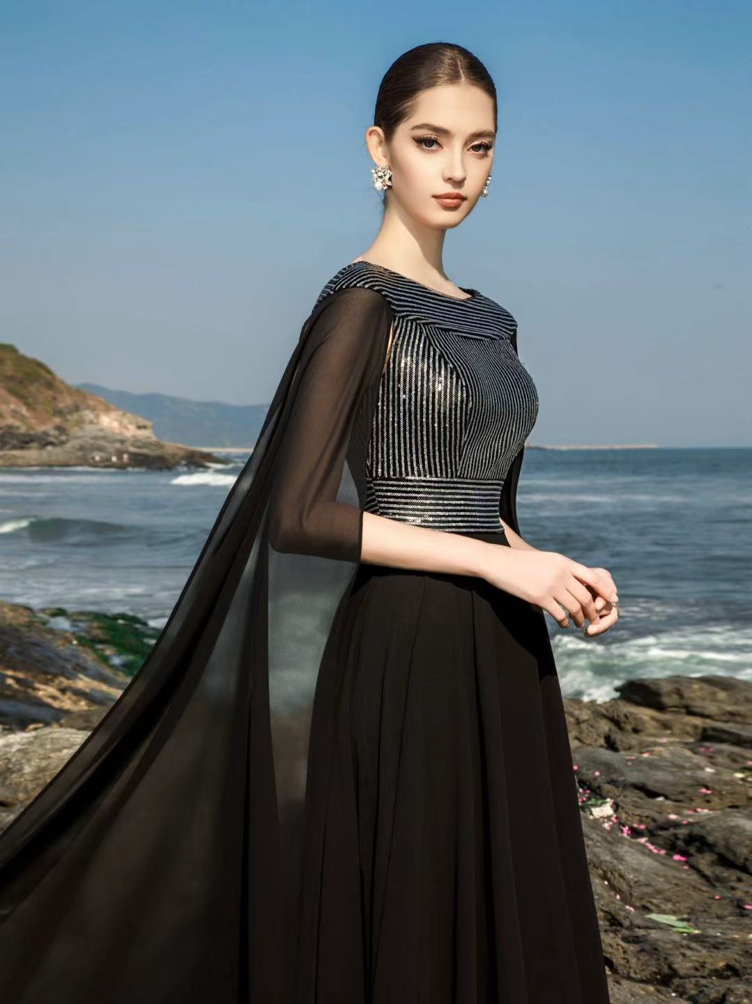 Vestido de noche negro con adornos hechos a mano, fotografiado junto al mar